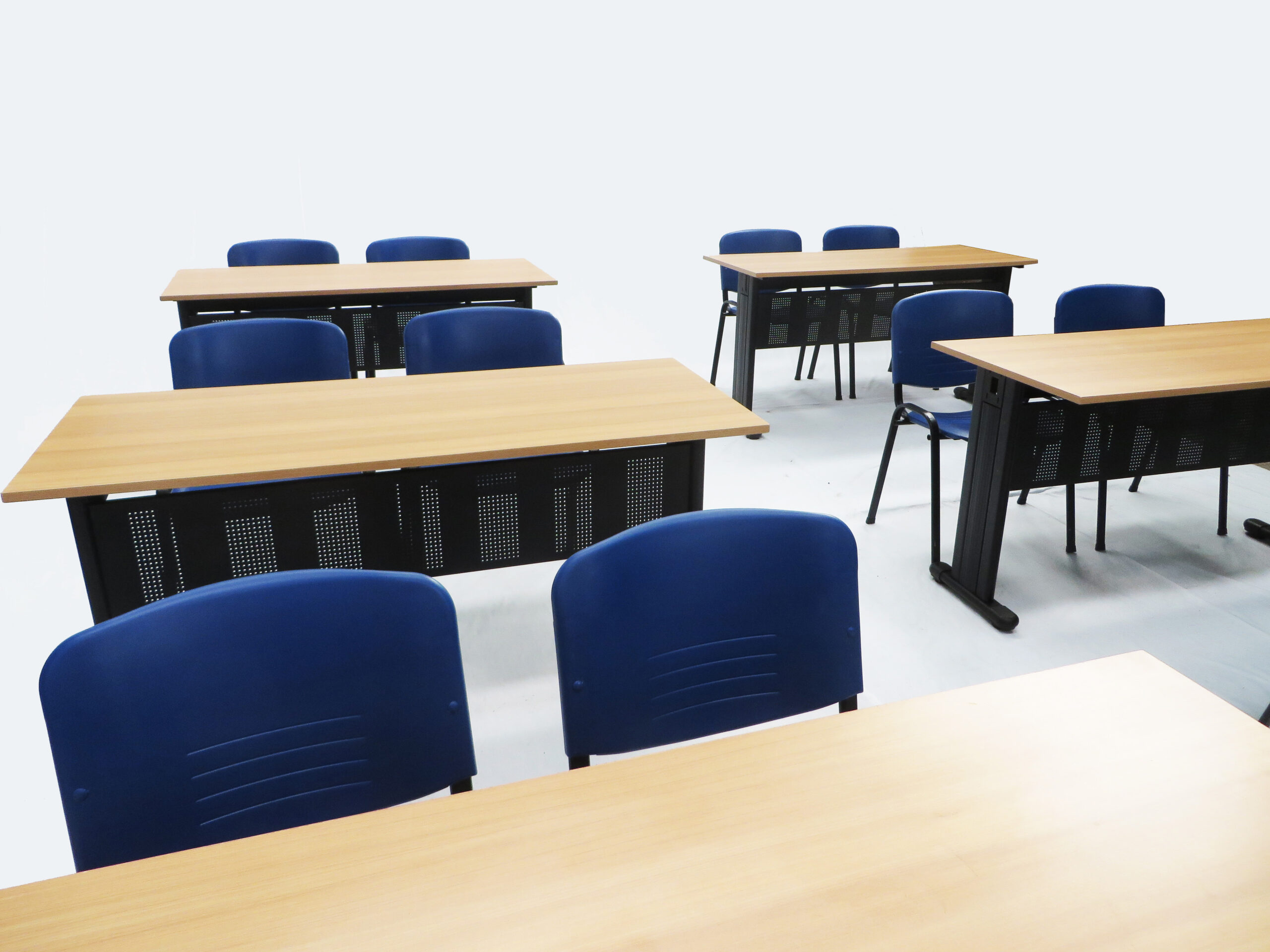 Capacitación con sillas universitarias distribuidas en filas